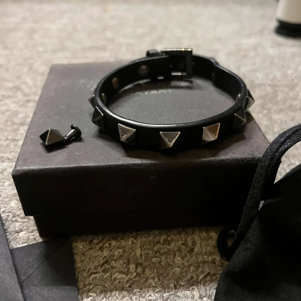 Snyggt svart armband från Valentino med silverfärgade nitar. Armbandet är justerbart och kommer i originalförpackning med en liten påse för förvaring. Mycket bra skick, extra nitar fås med!. Asusteet.