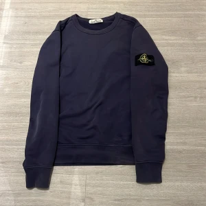 Mörkblå tröja från Stone Island - Säljer en snygg mörkblå tröja från Stone Island med deras ikoniska märke på ärmen. Tröjan är äkta och köpt på nk i Stockholm. Säljer den då den tyvärr inte kommer till användning längre skick 8.5/10, Inga hål bara lite urtvättat därav priset. 💸Hör av dig vid övriga frågor. 