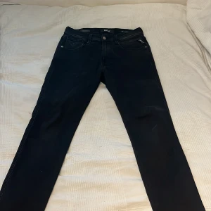 Svarta jeans från Replay anbass  - Snygga svarta jeans från Replay i modellen Hyperflex Anbass. De har en klassisk femficksdesign med knapp och dragkedja framtill. Perfekta för en stilren look.