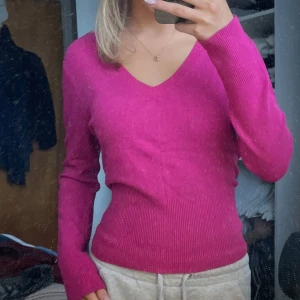 Rosa tröja från Tricotonic - Säljer en snygg rosa tröja från Tricotonic med v-ringning. Tröjan har långa ärmar och en ribbad kant vid ärmslut och nederkant. Perfekt för att liva upp garderoben med lite färg!