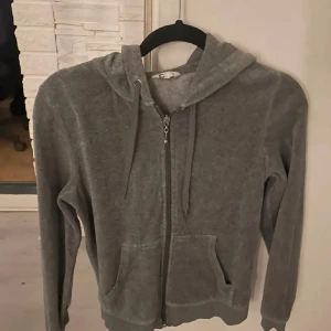 Grå hoodie med dragkedja - Säljer en mysig grå hoodie med dragkedja och huva. Perfekt för avslappnade dagar. Den har långa ärmar och praktiska fickor framtill.