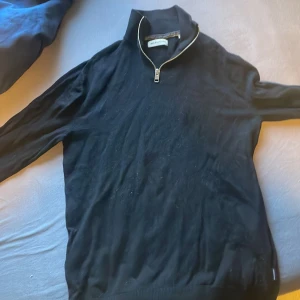 Svart tröja med dragkedja från Jack and Jones  - Snygg svart tröja från Jack and Jones Man med dragkedja vid halsen. Perfekt för en stilren look. Tröjan har långa ärmar och en bekväm passform.