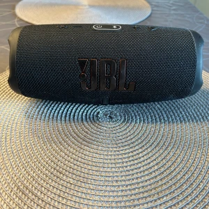 JBL CHARGE 5  - En JBL charge 5 väldigt bra ljud och funkar utmärkt liten repa på en av bokstäverna men syns knappt vid frågor så kan ni kontakta mig ett original pris ligger ungefär på 1900 kr.