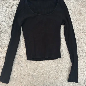 Svart och vit ribbad topp - Säljer två likadana ribbade toppar i svart och vit färg. Båda har en rundad hals och långa. De är stretchiga och bekväma, idealiska för både vardag och mer dressade tillfällen.