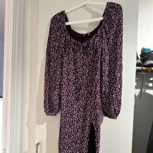 Blommig klänning med slits på låret - En superfin blommig klänning med slits på låret, väldigt stretchig. Snören från för att kunna knyta en rosett vid bysten: Storlek 40 men skulle säga att den passar 38/40