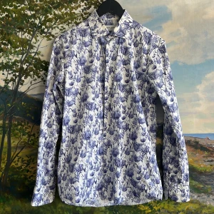 Blommig skjorta från John Henric - Säljer en stilren blommig skjorta från John Henric i blått och vitt. Skjortan har långa ärmar och ett klassiskt kragmönster. Perfekt för en elegant look.