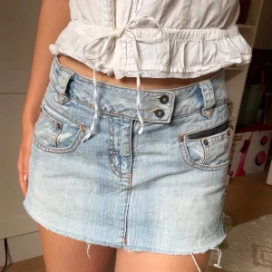 Lågmidjad jeanskjol  -  Ljusblå jeanskjol i denim!! Kjolen har dubbla knappar i midjan och en dekorativ dragkedja på ena fickan 😍Måtten är med på bild och jag bär vanligen storlek s