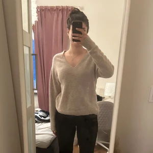 Beige stickad tröja med v-ringning - Säljer en mysig beige stickad tröja med v-ringning. Tröjan har långa ärmar och en avslappnad passform, perfekt för kyligare dagar. Passar bra till både jeans och kjol.