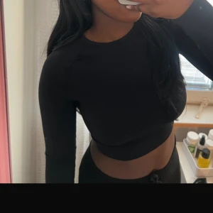 Svart croppad långärmad topp - Snygg svart croppad topp med långa ärmar. Perfekt för en stilren look. Passar bra till både jeans och kjol.