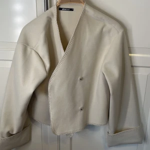 Beige jacka från Gina Tricot - Säljer en stilren beige jacka från Gina Tricot i storlek XS. Jackan har en omlott-design med knappar och långa ärmar. Aldrig använd!
