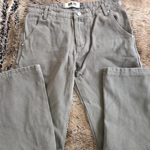 Grå cargobyxor från GALAG - Snygga grå cargobyxor från GALAG med praktiska fickor och en stilren design. Perfekta för höst- och vintersäsongen. Byxorna har en normal passform och är tillverkade i ett slitstarkt material.