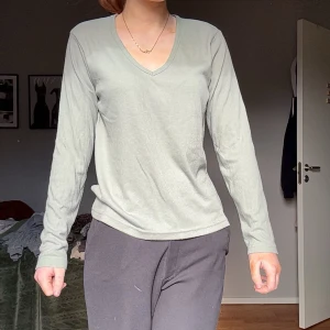 Grön ribbad långärmad tröja - Säljer en stilren grön ribbad tröja med v-ringning. Tröjan har långa ärmar och är perfekt för en avslappnad look. Passar bra till både jeans och mjukisbyxor.