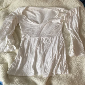 Vit långärmad blus från Design Si - Säljer en stilren vit blus från Design Si med långa ärmar och v-ringad hals. Klänningen har en elegant passform och är tillverkad i ett mjukt material. Med tillhörande snöre för att knyta! Väldigt fin på sommaren!!