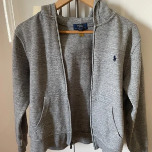 Grå och marinblå hoodies från Ralph Lauren - Säljer tre stilrena hoodies från Ralph Lauren. En i grått och två i marinblått, alla med dragkedja och den klassiska loggan på bröstet. Perfekta för en avslappnad stil. 🧥Storlekarna på den grå hoodin är 14-16 och en av de blå sen den andra blå är i storlek 18-20. Storlekarna mostsvarar XS-S. Säljer tröjorna för 349kr/st annars alla 3 tillsammans för 750kr. Nypris 1200kr/st