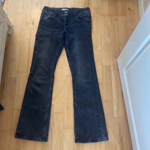 Bootcut jeans från Gina Tricot - MörkGråa bootcut jeans från Gina Tricot med klassisk femficksdesign och dubbla silverknappar i midjan. Jeansen har breda benslut och snygga detaljer på bakfickorna. Perfekt för dig som gillar retrovibbar och vill ha en cool siluett.