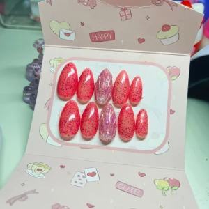 Rosa glitter press-on naglar - Säljer ett set med 10 st press-on naglar i en snygg rosa färg med rosa glittereffekt. Två av naglarna har en transparent bas med iriserande flakes som ger extra bling. Naglarna är mandelformade och har en glansig finish, perfekta för att ge dina händer en poppig look.