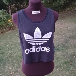Adidas croptop - Cool croptop från Adidas i svart med stort vitt tryck framtill. Loggan är lite sliten. Storlek s men har en loose passform så passar även m. Välanvänd men väldigt skön🤍⚽️🖤