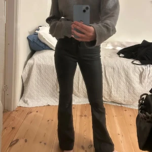 Svarta bootcut jeans - Säljer ett par svarta jeans med bootcut-snitt som sitter snyggt över höfterna och har utsvängda ben. De har klassisk femficksdesign och hög midja, perfekta för en trendig och stilren look. Passar dig som gillar en tidlös vibe och vill ha ett par jeans som sticker ut.