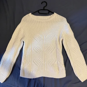 Vit stickad tröja från MNG - Säljer en vit stickad tröja från Mango med snyggt strukturerat mönster och rund hals.  Storlek 140.                                                     Tröjan har långa ärmar och ribbade muddar vid hals, ärmslut och nederkant. Det är en lite luftigare modell, perfekt över tex ett linne:)