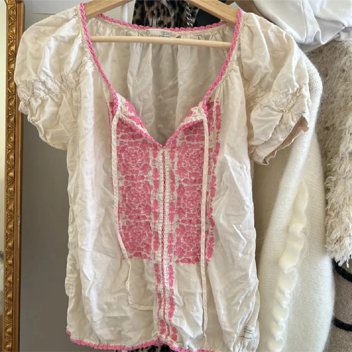 Vit blus med rosa broderi och snörning