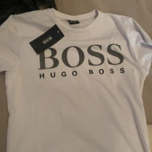Vit t-shirt från Hugo Boss - Snygg vit t-shirt från Hugo Boss med stor svart logotyp på bröstet. Kommer utan tagg!!