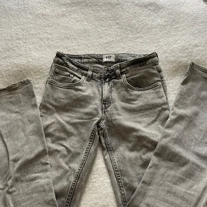 Grå bootcutjeans - Snygga grå jeans från lager 157 med klassisk femficksdesign och raka ben. Jeansen har en neutral grå tvätt och detaljer som knapp och dragkedja framtill. Passar dig som gillar en enkel och stilren look. Materialet är jeans och de har normal passform.
