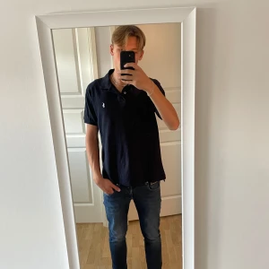 Mörkblå pikétröja från Ralph Lauren - Tjena säljer nu min snygg mörkblå pikétröja från Polo Ralph Lauren med klassisk krage och korta ärmar tröjan är i custom slim fit. Tröjan är i 10/10 skick och har inga tecken på användning. Tröjan har en vit broderad logga på bröstet och är gjord i mjuk bomull. Perfekt för speciella tillfällen och till vardags. Priset är inte hugget i sten!