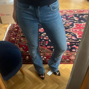 Blå bootcut jeans med låg midja  - Snygga blå jeans med bootcut passform och rå, fransad kant vid benslut. Klassisk femficksmodell och medelblå tvätt som ger en cool och avslappnad vibe. Passar uppskattningsvis 160-165cm och storlek Xs-S