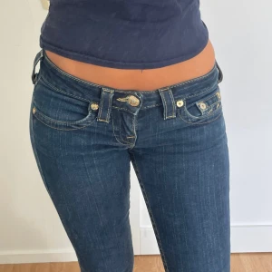 Jeans - Jättesnygga lågmidjade straight/bootcut jeans från True Religion. Modellen heter ”Johnny”. Midjemåttet tvärs över är 36 cm och Innerbenslängden är 88.5 cm. Jag är 170 och brukar ha 25-26 i jeans och de passar väldigt bra på mig.