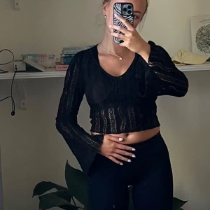 Svart croppad spetsblus  - Säljer en svart croppad blus från Shein med långärmade trumpetärmar och v-ringad hals. Blusen är gjord i genombruten spets med ett subtilt randigt mönster och har en riktigt snygg, feminin vibe. 