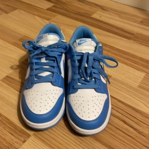 Nike Dunk low university blue - Nike dunk low med fräscha färger, har använt max 10 ggr och är för små för mig så jag säljer! Storlek 43. 
