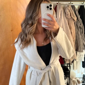 Beige kappa med huva från Zara - Snygg beige kappa med stor huva och knytbälte i midjan.  Nästan aldrig använd och har inga defekter. Som ny. 