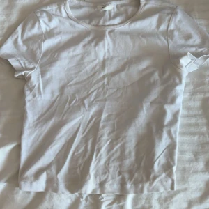 Vit basic t-shirt - En klassisk vit t-shirt med rund hals och korta ärmar. Modellen är enkel och passar perfekt till jeans eller shorts. Tillverkad i mjuk bomull som känns skön mot huden. Perfekt för dig som gillar minimalistisk stil. Likadan i svart också.