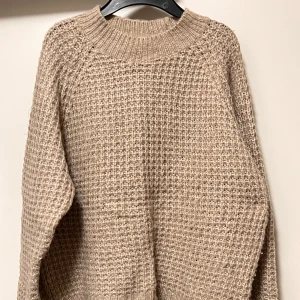 Beige stickad tröja från 157 - Säljer en beige stickad tröja från 157 i storlek XS. Tröjan har ett grovt, strukturerat stickmönster och ribbad halsringning. Perfekt för dig som gillar en chill och cozy vibe under höst och vinter. Passar dig som vill ha en enkel men snygg look.