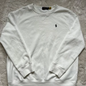 Vit sweatshirt från Polo Ralph Lauren - Vit sweatshirt från Polo Ralph Lauren med rund halsringning och broderad logga på bröstet. Tröjan har långa armar och är använd ett fåtal gången.