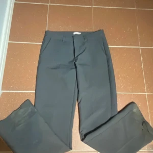 Mörkgrå kostymbyxor med rak passform - Snygga mörkgrå kostymbyxor från Nelly.  Byxorna har sidfickor, perfekta för en clean och stilren look. Materialet känns slätt och dressat. Endast använda 1 gång!