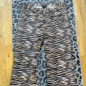 Tuffa jeans från Monki - Ett par jättesnygga byxor i stretchig twill med låg och bootcut/lite utställda ben från Monki. De har en gylf med dragkedja, fickor med lock och bakfickor. Smal passform i låren Låg midja. Bootcut ben. Gylf med dragkedja. Fickor med lock. Bakfickor. Stretchig twill Dom är helt nya, bara testade! Storlek large-Passar 38/40 Längd: 105cm Innerbenslängd: 82cm Midjan: 41x2cm