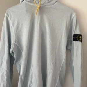 Ljusblå hoodie från Stone Island - Säljer en fräsch ljusblå hoodie från Stone island, nyskick och den är inte använd, kvittot finns även och tröjan är i storlek M skulle nog passa även i S. Priset diskuteras vid en snabb affär 