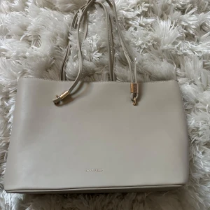 Beige axelväska från Anna Field - Snygg beige axelväska från Anna Field med stilren design och guldfärgade detaljer. Väskan har flera fack inuti, inklusive ett med dragkedja, och stängs med magnetknapp. Perfekt storlek för att få plats med allt du behöver under dagen. Aldrig använd! Tar frakt!