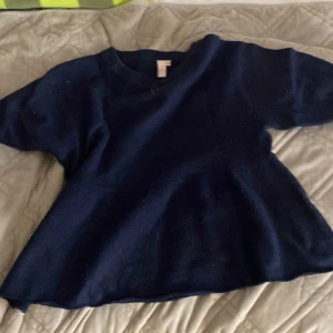 Mörkblå stickad tröja från Nelly - Säljer en mörkblå stickad tröja från Nelly i storlek XS. Tröjan har en rund halsringning och korta ärmar, perfekt för lager-på-lager under kyliga dagar. Den har en loose passform som ger en chill och avslappnad vibe.