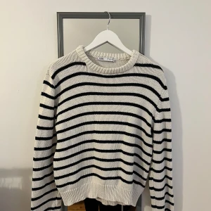 Randig stickad tröja  - Randig stickad tröja med guld knappar på ena axeln