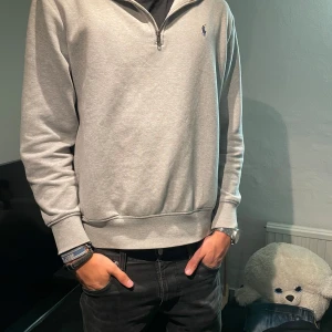 Grå half zip tröja från Polo Ralph Lauren - Snygg grå långärmad tröja från Polo Ralph Lauren med half zip. Tröjan har en normal passform och är storlek L, passar mig som är 193cm 78kg. Priset är ej hugget i sten.