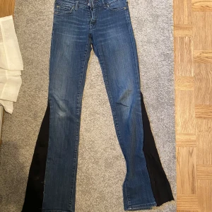 bootcut jeans med svarta slitsar - Blå jeans med bootcut passform och svarta tygslitsar längs bensidorna. Klassisk femficksmodell med medelhög midja och dragkedjegylf. Jeansen har en snygg tvätt och är tillverkade i jeansmaterial.