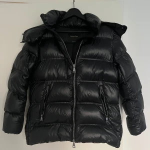 Massimo Dutti Puffer/Vinter Jacker - Säljer en svart pufferjacka från Massimo Dutti i storlek XS. Jackan har en glansig finish, huva och två dragkedjefickor framtill. Inga defekter. Pris kan diskuteras!💕