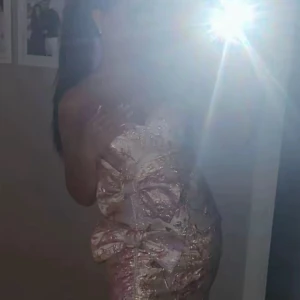 Rosa  kort klänning med rosetter - Superfin axelbandslös kort klänning i rosa med glittriga detaljer och två stora rosetter framtill. Klänningen har en figurnära passform och är perfekt för dig som vill sticka ut. Materialet har en lyxig känsla och skimrar snyggt i ljuset. Bara använd en gång.