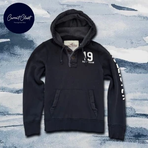 Svart hoodie från Hollister med tryck - Svart hoodie från Hollister med broderat vitt tryck '19 Surf Team' på bröstet och stort | Size M och passar true to size | Vintage men få slitningar förekommer
