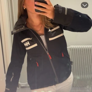 Helly Hansen jacka  - Så snygg helly Hansen sailing jacket🩵inte säker på att jag vill sälja men vill kolla om någon är intresserad. Röd luva bak och röda detaljer😊