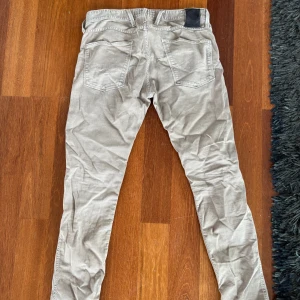 Beige Replay Anbass jeans herr - Snygga beige Replay Anbass jeans med klassisk femficksdesign och smal passform. Jeansen har en diskret logga på bakfickan och är tillverkade i mjuk bomull med lite stretch för extra komfort. Perfekta för en avslappnad och stilren look.