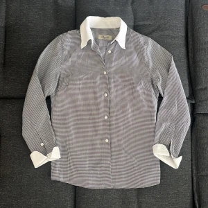 Rutig skjorta från Stenströms, svartvit - Snygg svartvit rutig skjorta från Stenströms med vit krage och vita manschetter. Klassisk passform med knappar framtill och lång ärm. Perfekt för dig som gillar stilrena detaljer och tidlös design. Den är super skick oanvänd