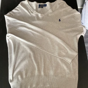 Beige tröja från Polo Ralph Lauren - Snygg beige långärmad tröja från Polo Ralph Lauren i slim fit. Tillverkad av mjuk pima bomull och har den klassiska blå broderade loggan på bröstet. Perfekt för dig som gillar stilrena och tidlösa plagg med en clean look.